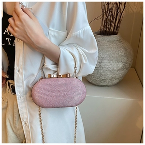 Close-up of pink glitter evening bag with gold handle, bow clasp and chain strap