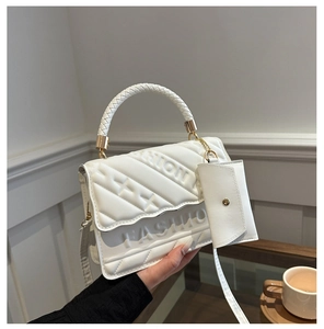 Close-up of quilted white handbag with woven handle and small coin purse attachment
