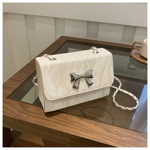 Close-up of cream white crossbody bag with marble texture and silver butterfly buckle