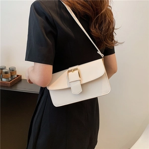 Minimalist beige leather shoulder bag with gold metal buckle on a dark dress model
