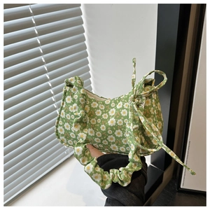 Close-up of green daisy pattern fabric and decorative side bow on a shoulder bag