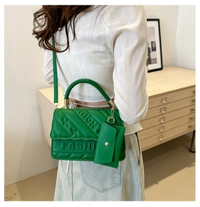 Detail view of bright green leather bag with FASHION embossed texture and mini pouch