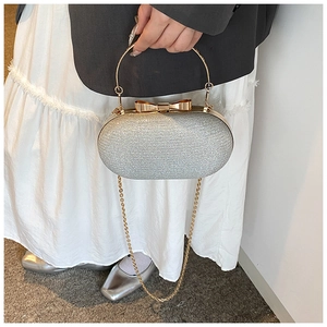 Close-up of silver sequin evening clutch bag with gold bow clasp and metal handle