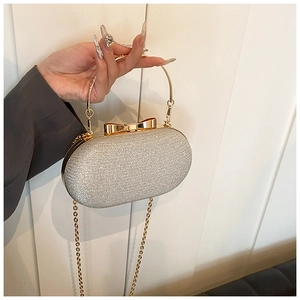 Detail of silver sequined evening bag with golden bow clasp and round handle