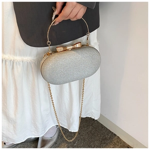 Detail of silver glitter evening bag with gold bow clasp and metallic handle