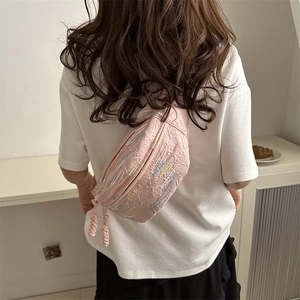 Pink crossbody dumpling bag with embroidered pattern and woven zipper on casual outfit