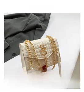 Détail du sac matelassé crème avec logo SS doré et pendentif à pompon élégant