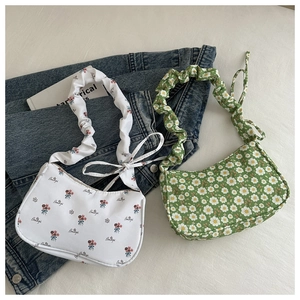Detail of floral underarm bags with ruffled straps and bows on denim background