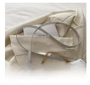 Detail of silver crocodile pattern bag with golden chain and leather shoulder strap