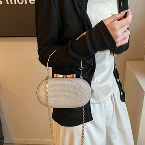 Sparkly silver evening clutch bag with gold round handle and bow clasp detail