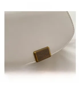 Macro shot of minimalist cream leather saddle bag with vintage textured gold hardware buckle