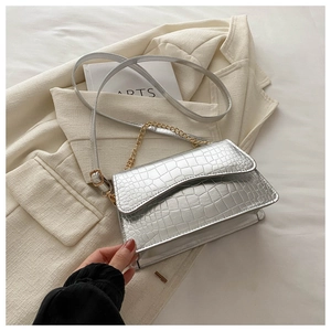 Detail view of silver crocodile texture bag with gold chain and wavy flap edge