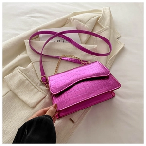 Detail of fuchsia crocodile pattern crossbody bag with gold chain on a white blazer