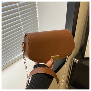 Detail of brown saddle bag with golden metallic lock and elegant chain shoulder strap
