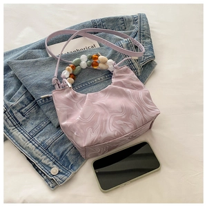 Détail du sac à main marbré lilas avec poignées en perles colorées et texture en cuir PU