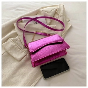 Detail of fuchsia crocodile pattern leather bag with gold chain and metal clasp