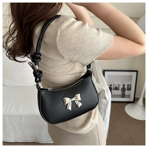 Detail of black leather underarm bag with silver butterfly buckle and knotted shoulder strap