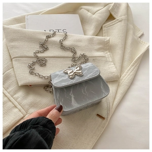 Vue détaillée de la texture marbrée bleu gris et de la boucle papillon argentée du sac