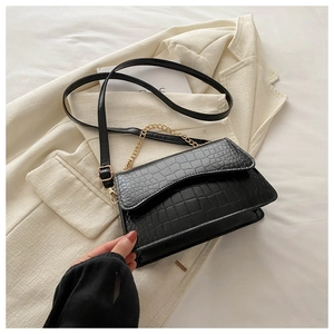 Close-up of black crocodile-embossed leather texture with gold metal chain strap detail