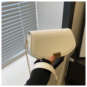 Detail of white saddle bag showing smooth leather texture and golden metal chain strap