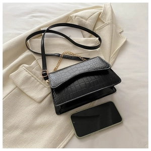 Detail of black crocodile pattern leather bag with gold chain and envelope flap design
