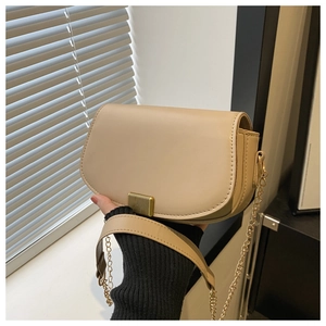 Close-up of beige saddle bag with textured leather and a golden stripe metal clasp
