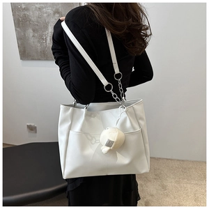 Borsa tote moderna in pelle bianca con catena e ciondolo di peluche su modella