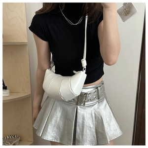Detail of white leather croissant bag featuring soft pleated texture and slim shoulder strap