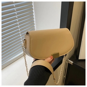 Detailed close-up of beige moon bag with gold striped clasp and chain strap