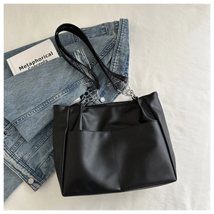 Dettaglio della borsa tote in pelle PU nera con catene argentate e tasche anteriori