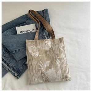 Close-up of champagne gold tote bag with bamboo leaf pattern and leather straps