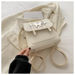 Detail view of cream white PU leather backpack with gold butterfly buckle and metal studs