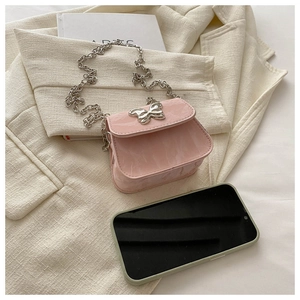 Détail du sac bandoulière rose à texture marbrée avec boucle papillon et chaîne argentée