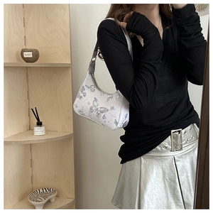 Detailed side view of a white butterfly print hobo bag worn by a model in a trendy style