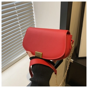Detail of red leather crossbody bag featuring gold metal buckle and elegant chain strap