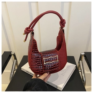 Detail of red crocodile texture handbag with gold buckle and twisted leather handle