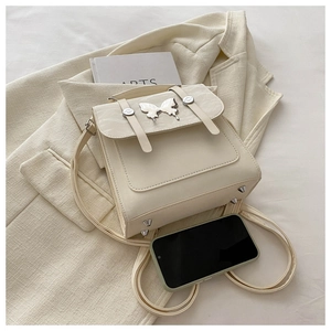 Detail of cream mini backpack showing silver butterfly hardware and metal feet