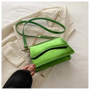 Detail of bright green crocodile embossed bag with gold chain and thin shoulder strap