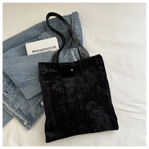 Detail view of black floral velvet handbag placed on denim for a vintage fashion look