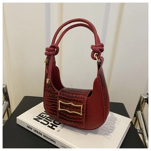 Detail of burgundy crocodile-embossed hobo bag with gold buckle and knotted handle