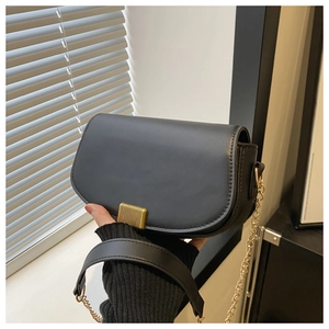 Detail of grey saddle bag featuring gold rectangular buckle and metal chain strap