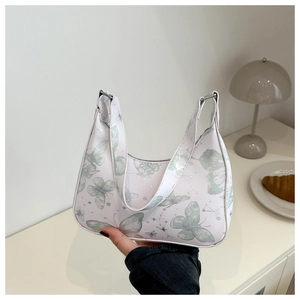 Close-up of white underarm bag with green butterfly prints and silver metal hardware detail