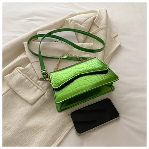 Detail of bright green crocodile embossed mini bag with gold chain and phone for scale
