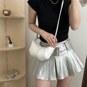 Fashionable white croissant crossbody bag with quilted pleats worn by a model