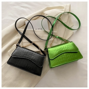 Detail of crocodile-embossed texture on black and green crossbody bags with gold chains