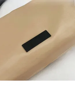 Detailed close-up of beige nylon crossbody bag featuring a black rectangular logo patch