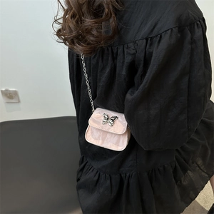 Mini sac bandoulière rose marbré avec boucle papillon argentée porté par un mannequin