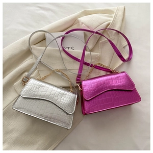 Detail of silver and rose red crossbody bags with crocodile texture and gold chains