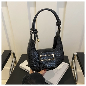 Detail of black crocodile texture crescent bag with knotted handle and gold metal buckle