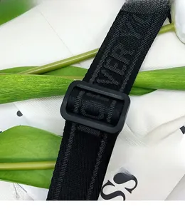 Detail of adjustable black woven shoulder strap with matte buckle and textured lettering